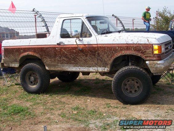 1989 Ford Bronco side view, white and brown two-tone, covered in mud