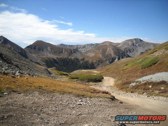 Mountain landscape with dirt road and SuperMotors logo