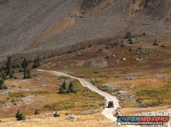 SUV driving up a dirt road on a rocky mountainside