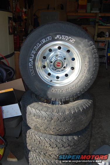 Stack of Goodyear Wrangler AT/S tires and chrome wheels