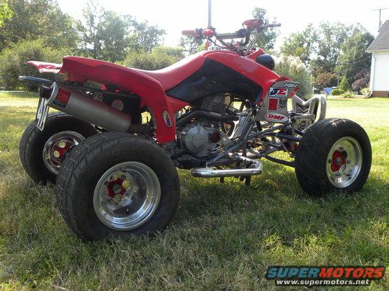 Red ATV with custom exhaust and chrome wheels, side view