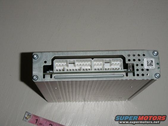 Car audio amplifier with multiple white connectors on top. A ruler is next to it