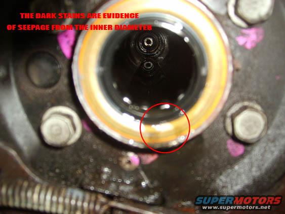 Close-up of a greasy automotive component with a red circle highlighting seepage