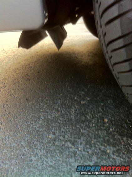 Close-up of a car's exhaust pipe and tire on asphalt