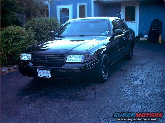 Black sedan parked in driveway, front end visible. License plate is visible