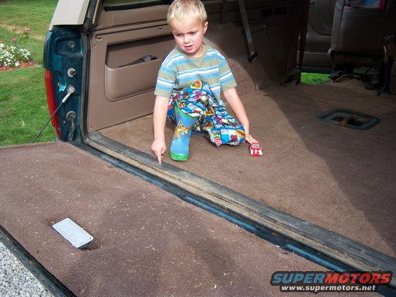 Child pointing at the carpeted cargo area of a vehicle