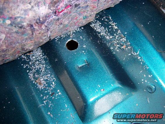 Teal interior floor with metal shavings and a drilled hole