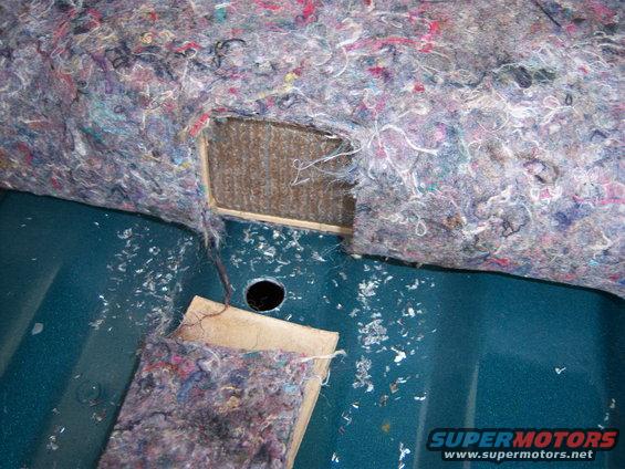 Interior paneling removed, showing insulation and exposed metal with a hole and wood bracing