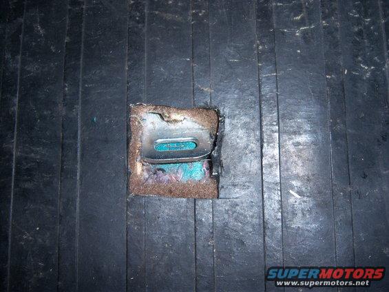 Close-up of a car's interior floor showing a cut-out for a child seat tether anchor