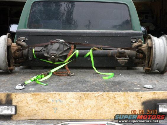 Rear axle assembly with wheels strapped to a truck bed