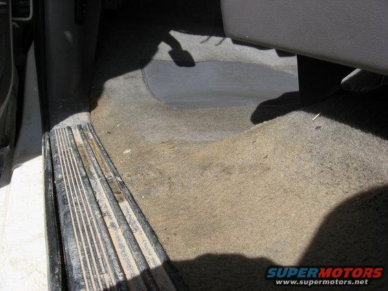 Interior floor of a vehicle with worn carpet and a metal step plate
