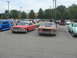1972 Ford Ranchero - This orange coupe with a prominent hood scoop is parked in a lot with other vehicles.