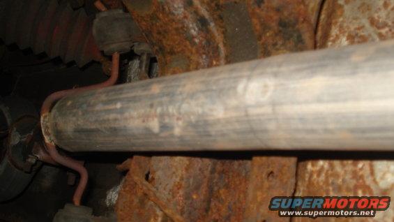 Exhaust pipe with red hangers attached to rusty frame components