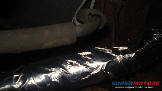 Close-up of vehicle exhaust pipe and shiny heat shielding