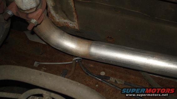 close-up of a vehicle's exhaust pipe and undercarriage with some rust visible