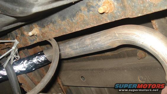 Close-up of rusted frame and exhaust pipe with foil-wrapped section