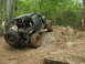 1996 Ford Bronco - An off-road vehicle navigates a challenging rocky terrain in a wooded area.