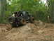1996 Ford Bronco - An off-road vehicle navigates a challenging rocky trail in a wooded area.