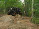 1996 Ford Bronco - Off-road vehicle navigating a challenging rocky path through a wooded area.