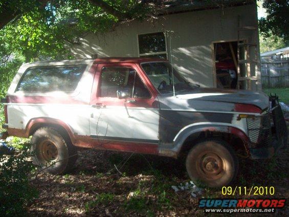 Red and white Ford Bronco with rust and primer patches, parked outdoors