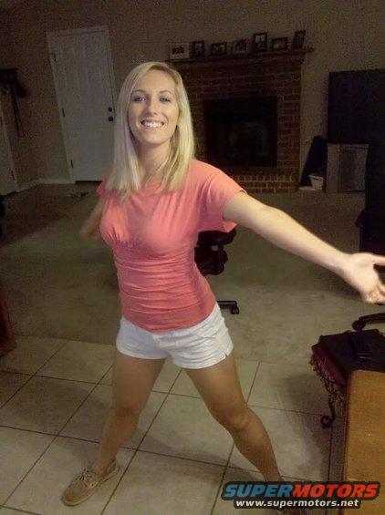 Woman in pink shirt and white shorts posing indoors