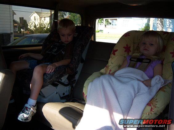 Interior view of a vehicle's back seat with two children in car seats