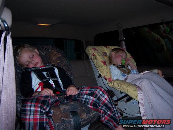 Two kids asleep in car seats in the back of a vehicle
