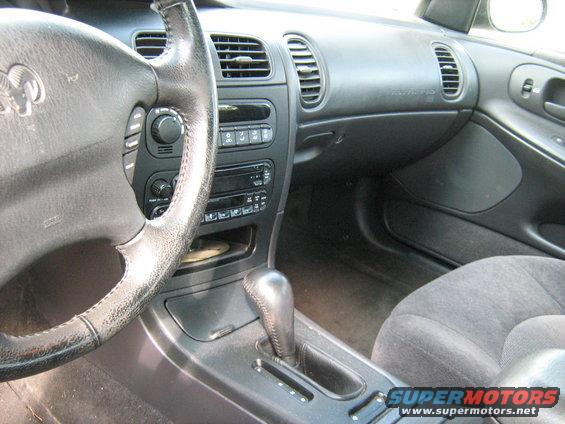 Interior shot of a Dodge Intrepid showing the steering wheel, dashboard, center console with gear shifter, and passenger seat