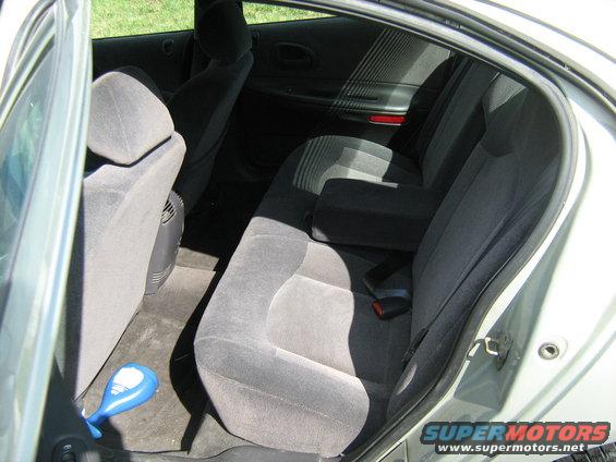 Interior rear seats of a car with gray upholstery and a blue object on the floor