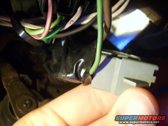 Close-up of a gray wiring harness connector with green and purple wires