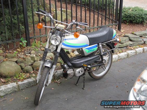 Motobecane moped with blue and green stripes on the tank. It has orange turn signals