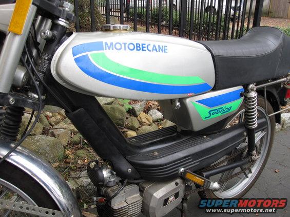 Motobecane Sebring moped side view, silver tank with blue and green stripes, black seat