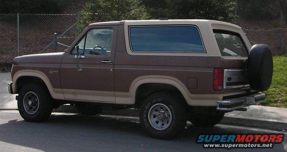 Brown and tan Ford Bronco parked on a street, side view. Spare tire mounted on the back
