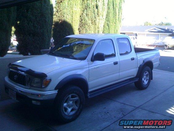 White Toyota Tacoma pickup truck, front 3/4 view, parked on concrete driveway