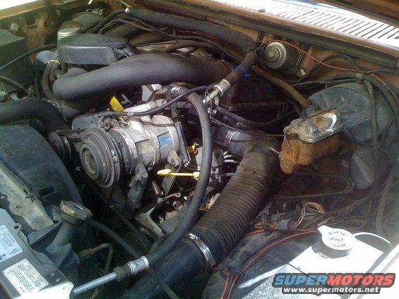 Engine bay with air intake, AC compressor, and brake fluid reservoir