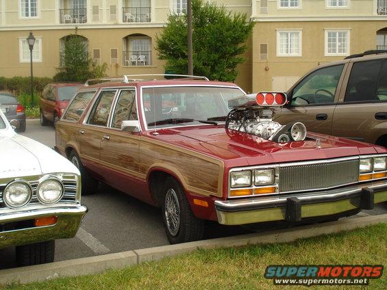 Red station wagon with wood paneling and a prominent supercharger on the hood