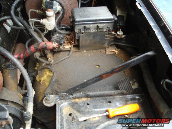 Engine bay showing fuse box, wiring harness, and a screwdriver on the battery tray