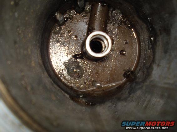 Close-up of a dirty engine oil filter housing with a metal fitting
