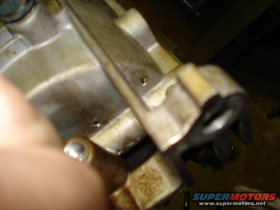 Close-up of a metal engine component with some grime and a black plastic bracket attached