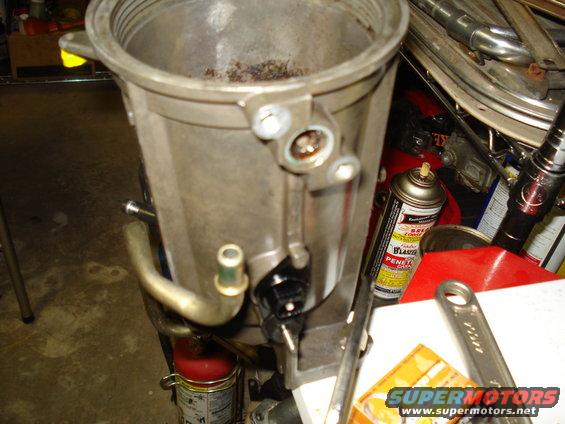 Aluminum intake manifold with debris inside, next to a can of penetrating oil