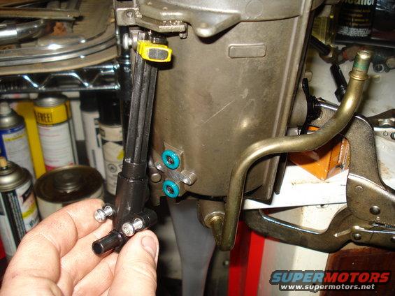 Close-up of engine part with fuel lines being held by a hand