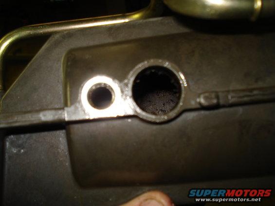 Close-up of an engine part with two circular openings, one small and one larger