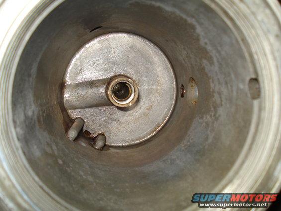 Inside of a carburetor, showing the bore, a central shaft, and some staining