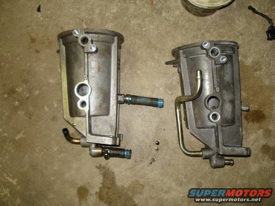 Two automotive fuel filters with metal and rubber hoses attached, lying on a concrete floor