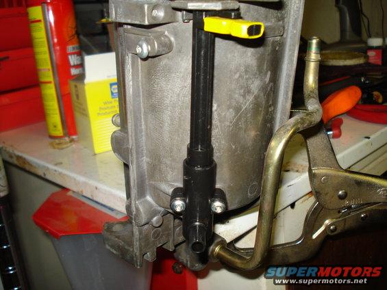 Engine part held by vise grips, with yellow lever and metal tube attached