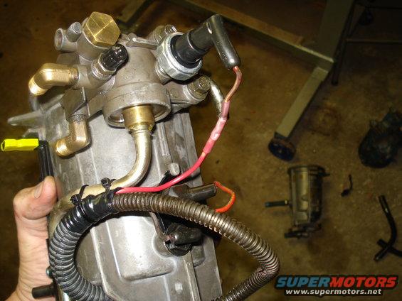 Engine part with brass fittings and red wire connected to a black cap