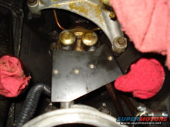 Close-up of engine parts, possibly a fuel pump, with red rags stuffed around it