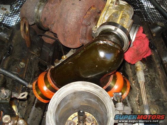 Turbocharger with orange and black banded intake piping, red rag, and engine components