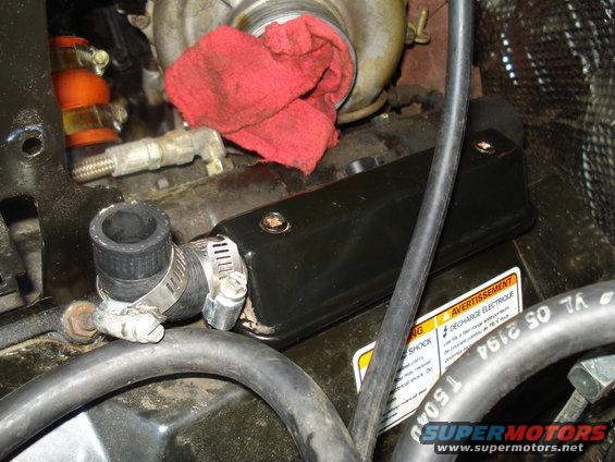 Engine compartment showing a turbocharger with a red rag stuffed in it, hoses, and a black cover
