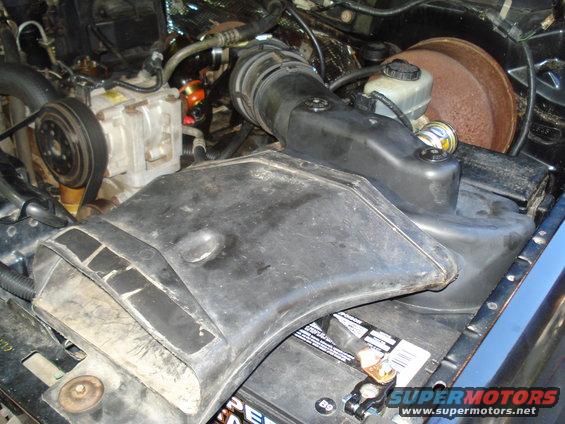 Engine bay with black air intake, battery, and brake booster